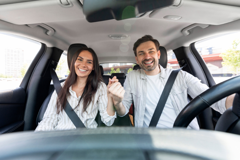 Excited loving couple sitting in car, holding hands and smiling