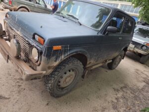 Schlammbedeckter blauer Lada Niva nach der Geländefahrt