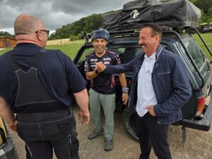 Viktor Derenko im fröhlichen Gespräch mit Teilnehmern vor einem Lada Niva mit Dachzelt
