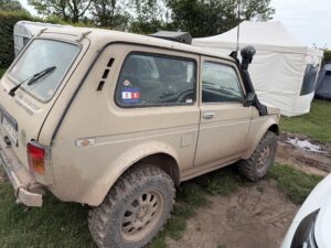 Sandfarbener, schlammbedeckter Lada Niva mit Schnorchel und Offroad-Umbau