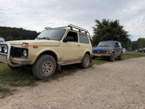 Zwei geländegängige Lada Niva mit Schlammspuren nebeneinander auf dem Treffen-Gelände