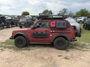 Rot lackierter Lada Niva mit Dachträger, Kanistern und Offroad-Ausrüstung